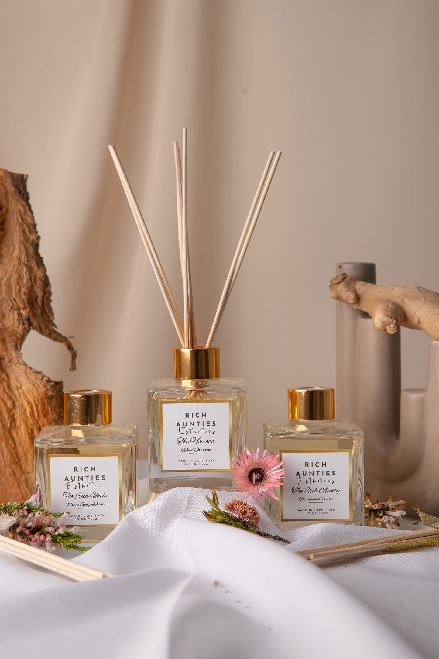 Reed diffuser trio on a neutral background with florals