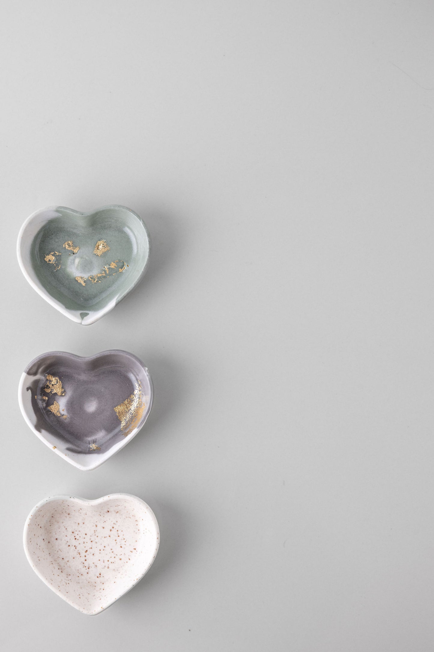 Three heart-shaped jesmonite dishes of different colors on a gray background