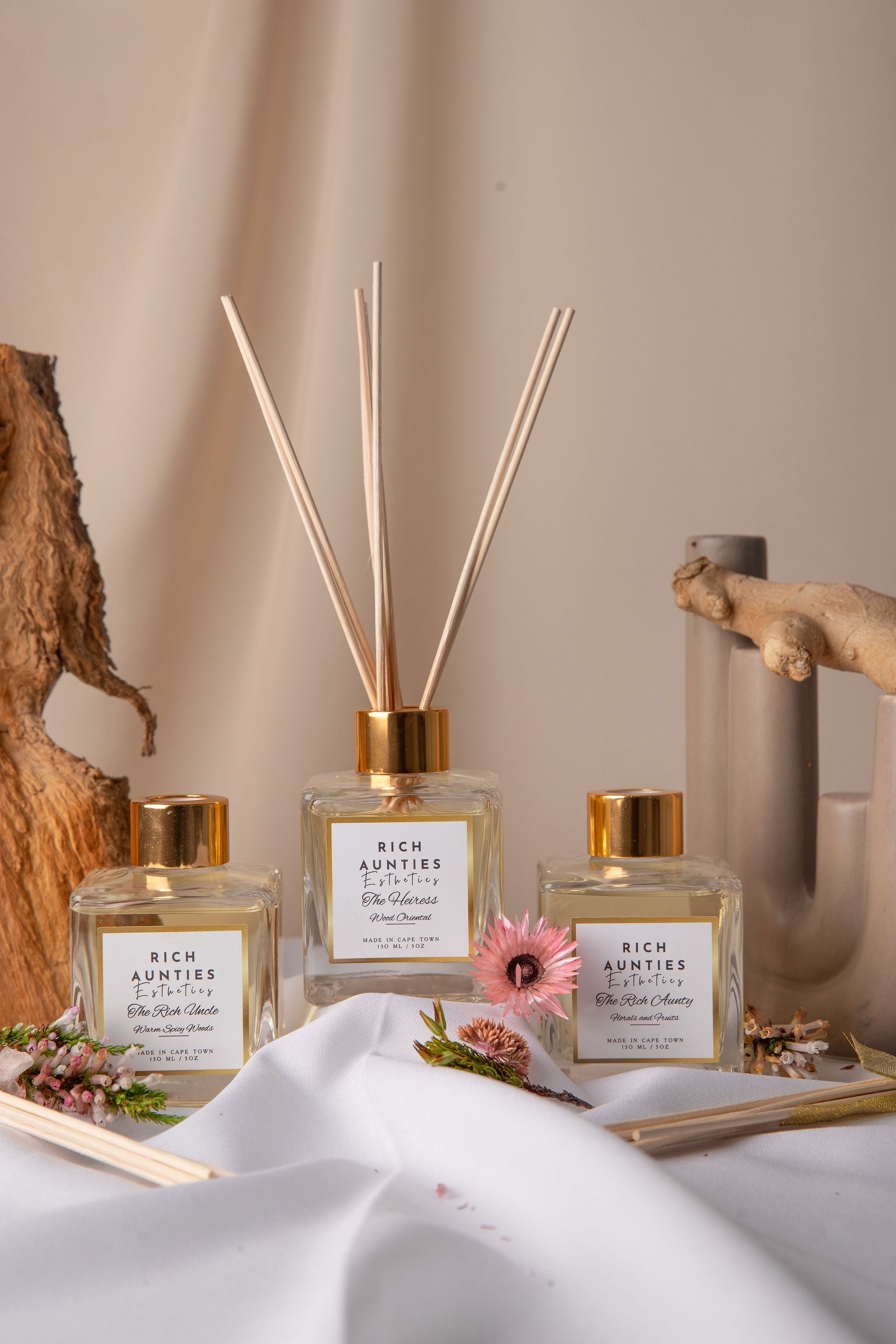 Reed diffuser trio on a neutral background with florals