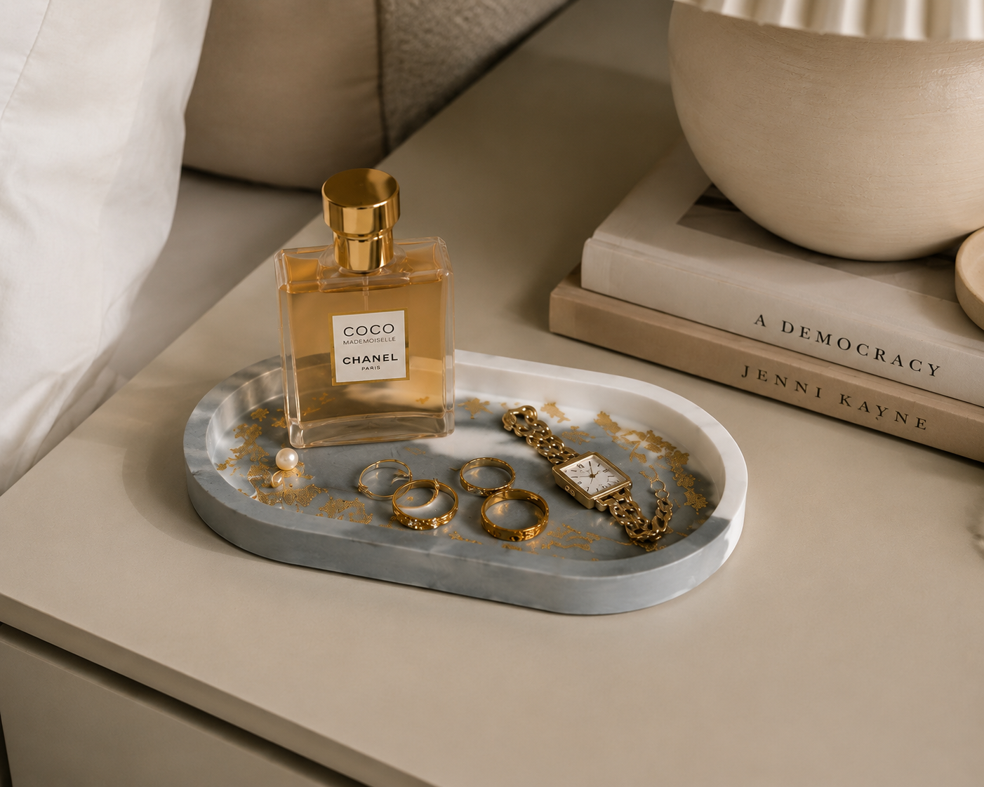 Chanel perfume bottle on a green marble gold leaf tray with jewelry on a beige surface